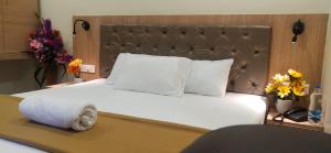 ein Schlafzimmer mit einem großen weißen Bett mit einem hölzernen Kopfteil in der Unterkunft Hotel Amutham in Tiruchchirāppalli + 20 Fotos