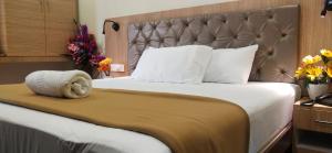 ein Schlafzimmer mit einem großen Bett mit großem Kopfteil in der Unterkunft Hotel Amutham in Tiruchchirāppalli