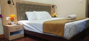 Schlafzimmer mit einem großen Bett mit einem Kopfteil aus Holz in der Unterkunft Hotel Amutham in Tiruchchirāppalli