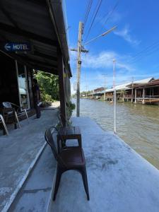 un banco sentado en un muelle junto a un río en Reuan Vilawan en Ratchaburi