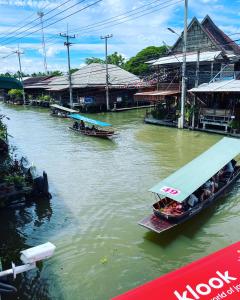 dos barcos en un río al lado de un edificio en Reuan Vilawan en Ratchaburi