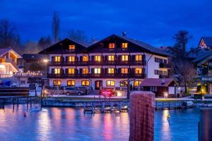 um grande edifício ao lado da água à noite em Gästehaus Grünäugl am See em Gstadt am Chiemsee