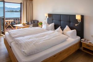 a large bed in a hotel room with a large window at Gästehaus Grünäugl am See in Gstadt am Chiemsee