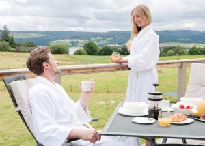 a woman in a bathrobe standing next to a man sitting at a table at Kessock Highland Lodges in North Kessock