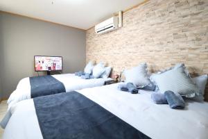 - une chambre avec 2 lits et un mur en briques dans l'établissement Osaka Arita Stay Ⅰ, à Osaka