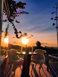 a table with two chairs on a deck with the sunset at Chalé Formoso - Chalé Romântico com Hidromassagem in Serra de São Bento
