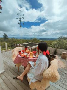 a woman sitting at a table in a teddy bear chair at Chalé Formoso - Chalé Romântico com Hidromassagem in Serra de São Bento