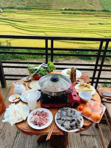 una mesa con platos de comida y una olla de comida en Dong Suoi H'mong Homestay & Bungalow en Mù Cang Chải