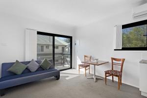 un soggiorno con divano blu, tavolo e sedie di Montego Mermaid Beach Motel a Gold Coast