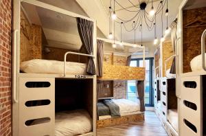 a room with three bunk beds in a room with a brick wall at Funtime Hostel in Chiayi City