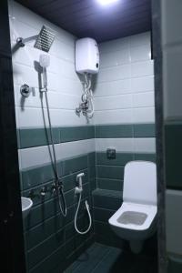 a green and white bathroom with a toilet and a sink at Dormitory Hub in Mumbai