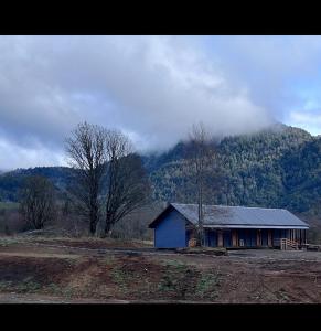 una pequeña casa azul frente a una montaña en Casa Huilo, en Neltume