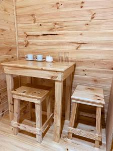 una mesa de madera y un taburete con tazones y tazas. en Casa Huilo, en Neltume