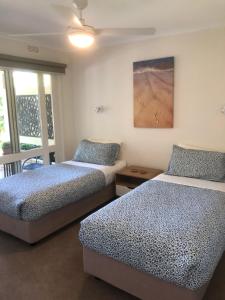 a room with two beds and a painting on the wall at Unit 13 Buckland Drive, Mallacoota in Mallacoota +2 photos