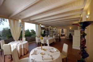un restaurante con mesas y sillas blancas y ventanas en Locanda Belvedere en Saludecio