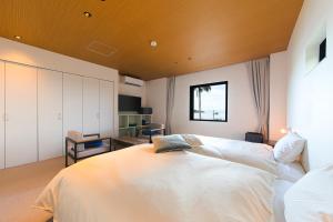 a bedroom with a large white bed with a wooden ceiling at セトノウツツ in Suo Oshima