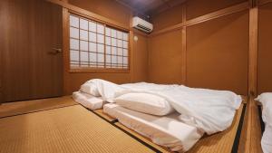 a bedroom with a bed with white sheets and a window at GUESTHOUSE YANAGIYA in Nakatsugawa