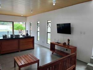a living room with a bench and a flat screen tv at Casa Tapera - Porto de Pedras/AL in Pôrto de Pedras