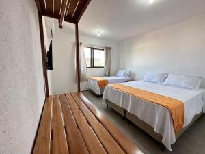a bedroom with two beds and a wooden floor at Casa Tapera - Porto de Pedras/AL in Pôrto de Pedras