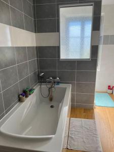 baño con bañera blanca y ventana en Charmant appartement en pierres, en Bourgoin
