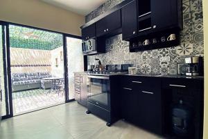 a kitchen with black cabinets and a stove top oven at Villa con Alberca Privada, 3 Recamaras 6 Personas in La Paz