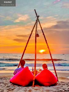 zwei Leute sitzen am Strand und beobachten den Sonnenuntergang in der Unterkunft HANZ AND Sunset Beach Resort in Phu Quoc