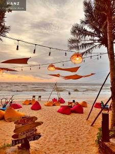 einen Strand mit einer Gruppe von Liegestühlen und Lichtern in der Unterkunft HANZ AND Sunset Beach Resort in Phu Quoc