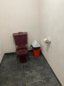 a bathroom with a toilet and a trash can at Farm Lodge La Cabaña 
