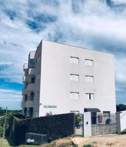 un bâtiment blanc avec une clôture devant lui dans l'établissement Apartamento belvedere do lago, à Serra Negra