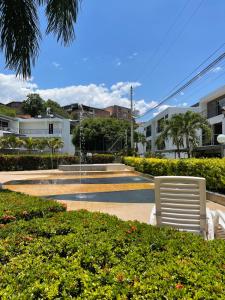 a park with two white chairs and bushes at Apartasol en Santa Fe de Antioquia in Santa Fe de Antioquia