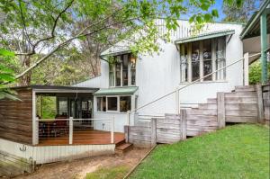 a white house with a deck and stairs at Mirimvale - Base of Mt Buller - Sleeps 14 in Merrijig