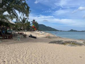 - une plage avec des tables et des chaises et l'océan dans l'établissement Paradise Bungalows Lamai Beach, à Koh Samui 