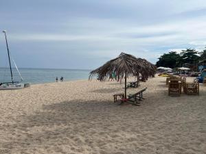 een strand met tafels en stoelen en een rieten parasol bij Paradise Bungalows Lamai Beach in Koh Samui 
