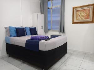 1 dormitorio con 1 cama grande con almohadas azules y moradas en Apartamento JM Vista Mar 6, en Río de Janeiro