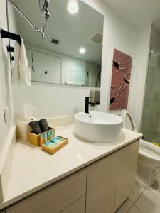 Baño blanco con lavabo y espejo en Beachwalk Resort & Condos, en Hallandale Beach