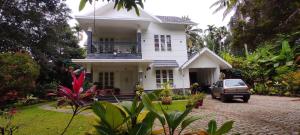 a white house with a car parked in front of it at ROBUSTA FOREST Home stay in Sultan Bathery