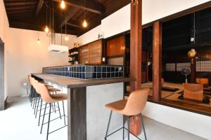 a kitchen with a bar with chairs around it at Togiso 能登の古民家宿 in Togi