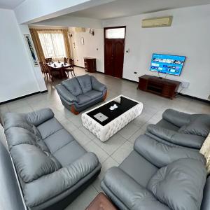 uma sala de estar com sofás, uma mesa e uma televisão em En-Suite Rooms W/Pool & Gym in Mikocheni Near Beach em Dar es Salaam