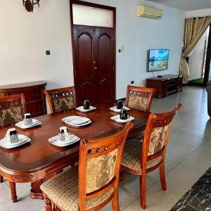 uma sala de jantar com uma mesa de madeira e cadeiras em En-Suite Rooms W/Pool & Gym in Mikocheni Near Beach em Dar es Salaam