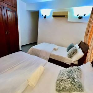 Habitación de hotel con 2 camas y sofá en En-Suite Rooms W/Pool & Gym in Mikocheni Near Beach, en Dar es Salaam