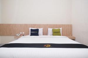 um quarto com uma grande cama branca e 2 almofadas em Urbanview Hotel DJ Inn Tegal em Tegal