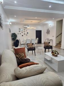 een woonkamer met een witte bank en stoelen bij Dvyne Luxury Home in Ikeja