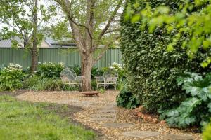 une passerelle avec des chaises et un arbre dans une cour dans l'établissement Elm Cottage, à Benalla
