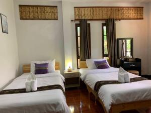 two beds in a room with two windows at Hotel Pailifornia in Pai