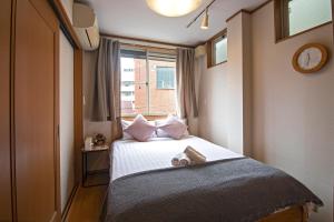 Dormitorio pequeño con cama y ventana en 五卧室别墅 毗邻大阪城公园 en Osaka