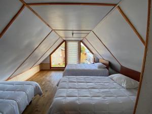 two beds in a room with two windows at Cabañas kavizke in Puerto Puyuhuapi