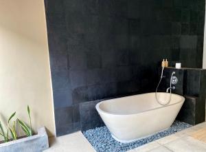 a bath tub in a bathroom with a black wall at Grey House Monkey Forest in Ubud