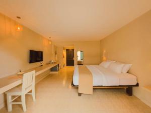 ein Schlafzimmer mit einem Bett, einem Schreibtisch und einem Fernseher in der Unterkunft Casa Solana in Patong Beach