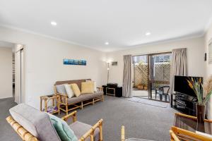 a living room with a couch and a tv at Pilot Bay Pad - Mount Maunganui Holiday Home in Mount Maunganui