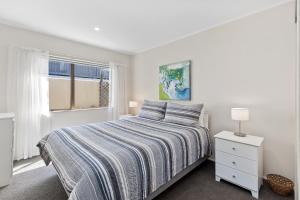 a white bedroom with a bed and a window at Pilot Bay Pad - Mount Maunganui Holiday Home in Mount Maunganui